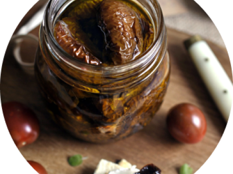 Frasco de vidrio con higos en almíbar sobre tabla, con uvas alrededor