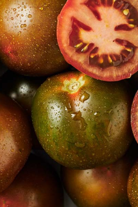 Tomates variados, algunos cortados, en tonos verdes, rojos y marrones.
