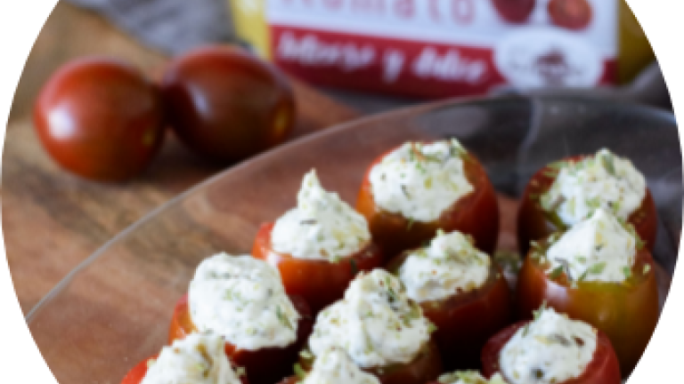 Tomates cherry rellenos de queso crema en un plato, con caja de mini kumato al fondo